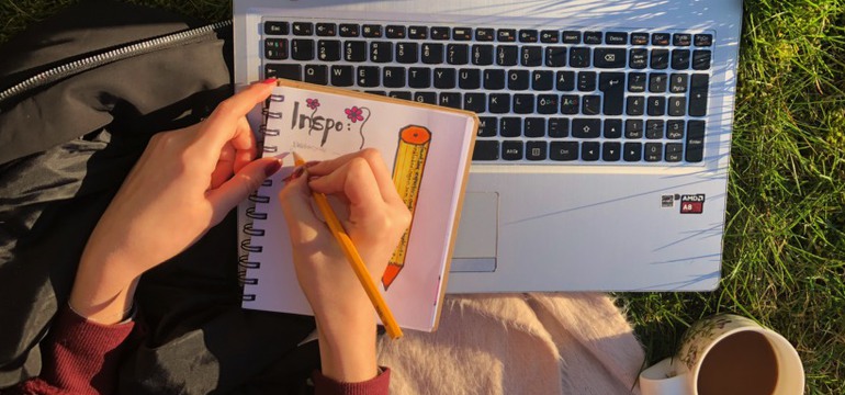 Bild av två händer som antecknar. Man ser bara händer, penna, papper, dator, en kopp kaffe, gräset på marken och ordet "Inspo".