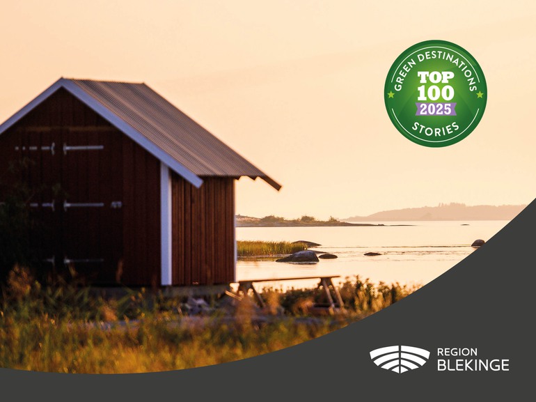 En liten röd stuga vid havet. Grön dekal med texten: Green destination stories top 100 2025