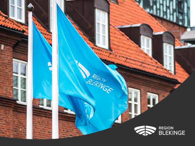 Närbild på Region Blekinges blåa flaggor. I nederkant ett svart fält med Region Blekinges vita logotyp.