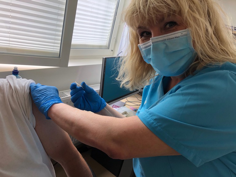 En person vaccinerar en patient mot covid-19.