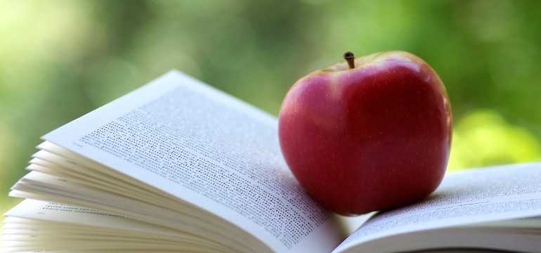 Ett äpple som ligger på en öppen bok