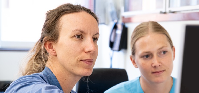 En specialistläkare och en intensivvårdssjuksköterska sitter framför en datorskärm.