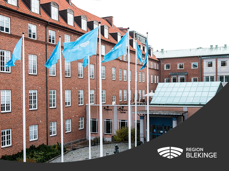 Flaggor i förgrunden. I bakgrunden en brun tegelbyggnad.