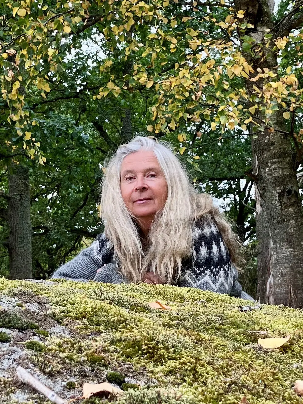 Stina Helmersson ligger på en mossig sten.